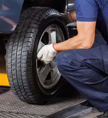 Low section of mechanic fixing car tire at auto repair shop